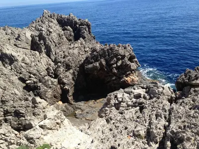 a rocky cliff with the ocean in the background at Villa Venere al Sauce - esclusiva villa sul mare in San Vito lo Capo
