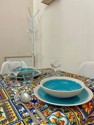 a table with plates and glasses on a colorful table cloth at Casetta Bedda in Palermo