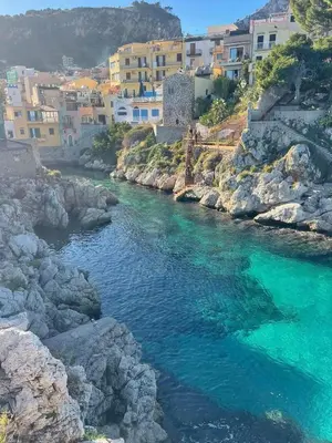 a river with turquoise water and buildings in the background at Casa Maria Elena in Santa Flavia