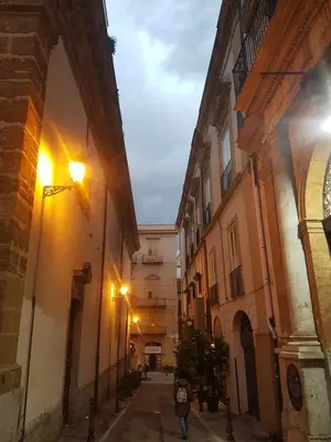 an alley with buildings and a person walking down a street at Vucciria room in Palermo