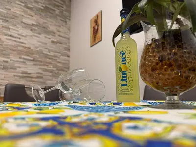 a table with a bottle and glasses and a vase at La Dolcissima in Castellammare del Golfo