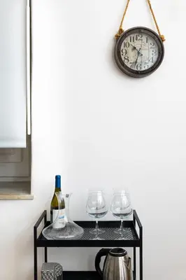 a shelf with wine glasses and a clock on a wall at 105 Apartments in Palermo