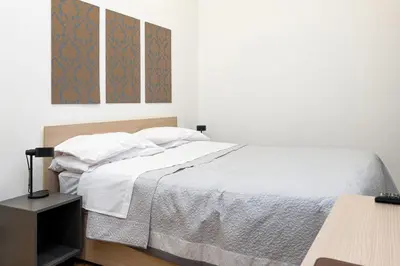 a white bedroom with a bed and a tv at 105 Apartments in Palermo