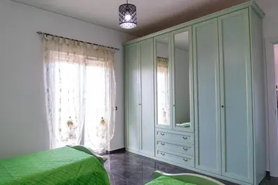 a bedroom with a green bed and a large window at Cuor di Leone in Corleone