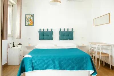 a white bedroom with a blue bed and a table at Villa Torre Ulisse Locazione Turistica Affitti Brevi in Carini