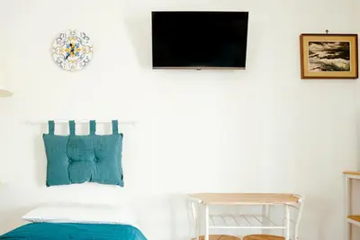 a bedroom with blue pillows and a tv on a wall at Villa Torre Ulisse Locazione Turistica Affitti Brevi in Carini