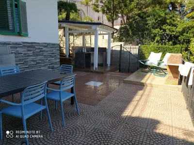 a patio with a table and chairs and a grill at Capozafferano-Casa Carola in Santa Flavia