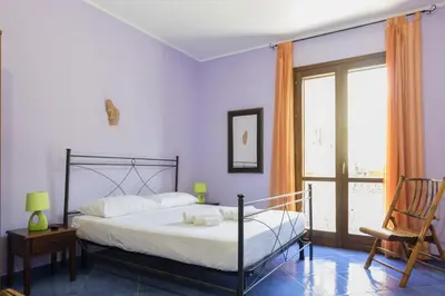 a bedroom with a bed and a chair and a window at Visitsicilia Le Magnolie in Castellammare del Golfo