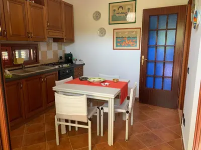 a kitchen with a table and some chairs and a table and a kitchen with at Villino Toti e Silvana - a 50 mt dal mare in Carini