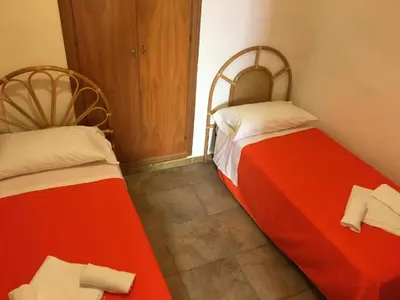 two beds in a room with red and white sheets at Terrasini 2000 Casa Vacanze in Terrasini