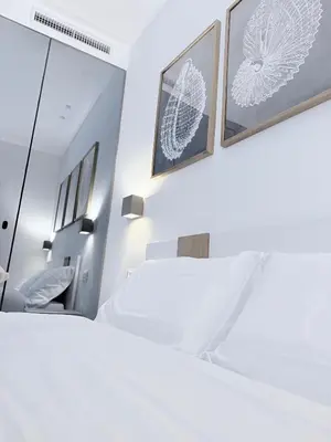 a bedroom with white furniture and framed pictures on the wall at Santa Rosalia Suites in Palermo