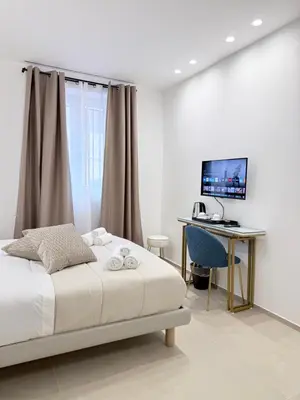 a bedroom with a bed and a desk with a computer at Santa Rosalia Suites in Palermo