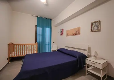 a bedroom with a blue bed and a crib at Casa Vacanze Verdemare in Mondello