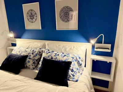 a bedroom with blue walls and a bed with pillows at Nova Holidays in Palermo