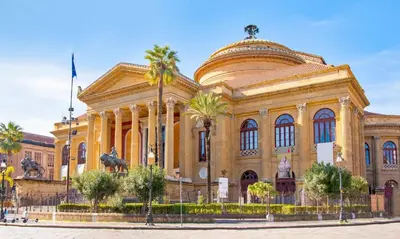 a large building with palm trees in front of it at Kàlia Rooms in Palermo