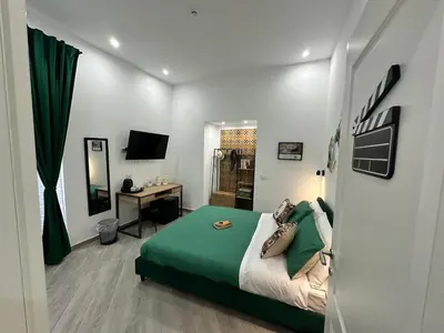 a bedroom with a bed and a desk with a television at Kàlia Rooms in Palermo