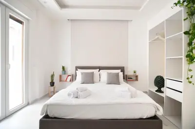 a white bedroom with a large bed with two towels at iFlat Casa Diamante in Palermo