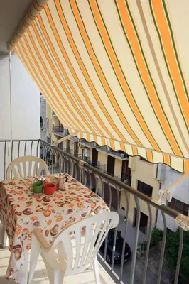 a table and chairs on a balcony with an umbrella at Pompei in Castellammare del Golfo