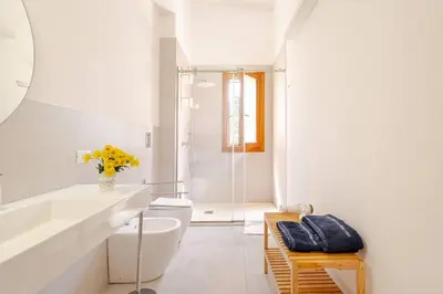 a white bathroom with a toilet and a sink at Villa Four by Sicily Travelling Villas in Scopello