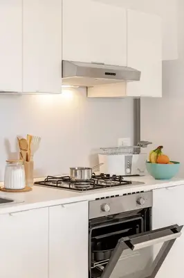 a white kitchen with a stove and a bowl of fruit at Villa Four by Sicily Travelling Villas in Scopello