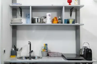a kitchen counter with a sink and some shelves at La Terza Porta in Palermo