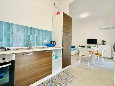 a kitchen with wooden cabinets and a dining room at Casa La Mamà, a 150 mt dal mare in Alcamo