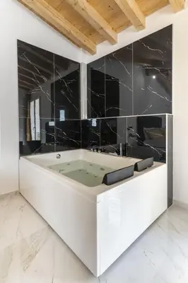 a bathroom with a bath tub with black tiles at Le Piccole Duse in Palermo