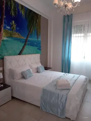 a bedroom with a large white bed with a painting on the wall at Dolce casa in Palermo