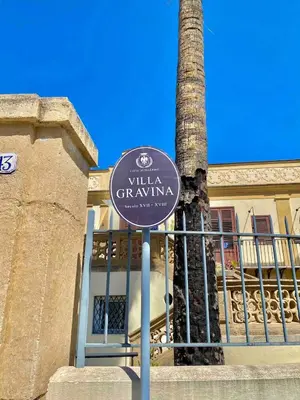 a white car parked in front of a building with palm trees at Apartment in Villa Storica Lanterna sul Mare Palermo in Palermo