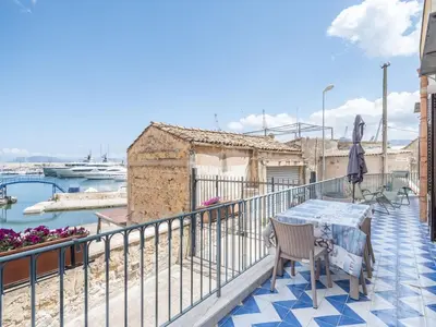 a marina with boats in a harbor with pink flowers at Apartment in Villa Storica Lanterna sul Mare Palermo in Palermo