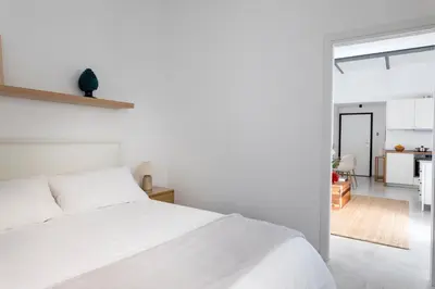 a bedroom with a white bed and a kitchen at With love, Apartment 4 in Palermo