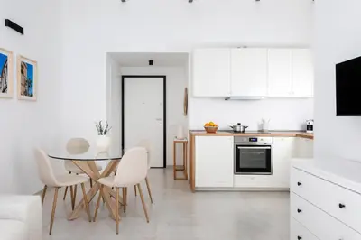a kitchen with white cabinets and a table and chairs at With love, Apartment 4 in Palermo
