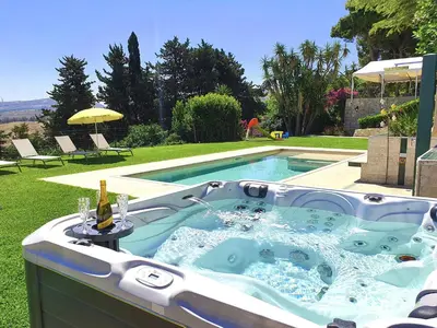 a hot tub in the yard with a bottle of wine at Villa Tommaso Maruggi, Sicilia, con Jacuzzi e piscina privata in Alcamo