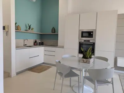 a kitchen with white cabinets and a table and chairs at Apartament and suite cavour 106 in Palermo