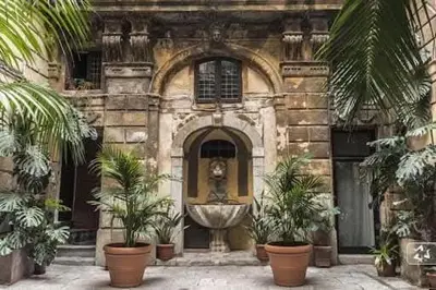 a stone building with a fountain in front of it at Palazzo Conte Federico Apartments in Palermo