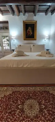 a bedroom with a large white bed with a painting on the wall at Palazzo Conte Federico Apartments in Palermo