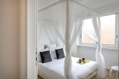 a bedroom with a white canopy bed with a window at Ruggero City View apartment by Wonderful Italy in Palermo
