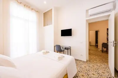 a white bedroom with a bed and a tv at Casa D'Ondes in Palermo