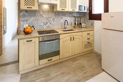a kitchen with wooden cabinets and a sink and a refrigerator at Beach View Apartment in San Vito lo Capo