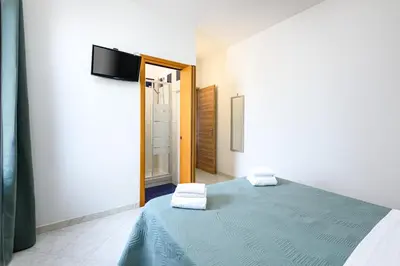 a bedroom with a blue bed and a tv on a wall at Beach View Apartment in San Vito lo Capo