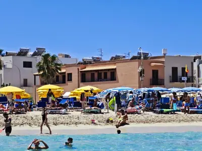 a group of people on a beach with umbrellas at Beach View Apartment in San Vito lo Capo