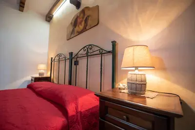 a bedroom with a red bed with a lamp on a table at Monolocale Casa Maria in San Vito lo Capo