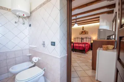 a bathroom with a toilet and a bedroom at Monolocale Casa Maria in San Vito lo Capo