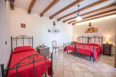 two beds in a room with red sheets at Monolocale Casa Maria in San Vito lo Capo