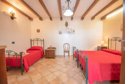 a bedroom with two beds and a table and chairs at Monolocale Casa Maria in San Vito lo Capo