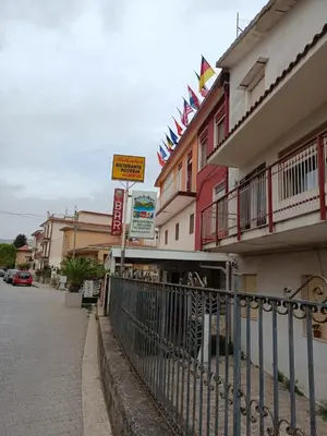 a building with flags on top of it next to a street at Albergo BELVEDERE in Santa Cristina Gela
