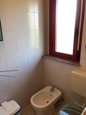 a bathroom with a toilet and a sink and a window at Albergo BELVEDERE in Santa Cristina Gela
