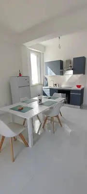 a white kitchen with a table and chairs in it at Casa Viola - Central Apartment City & Sea in Alcamo