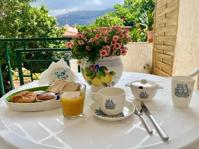 a table with a breakfast of coffee and a vase with flowers at Villa Melina in Carini