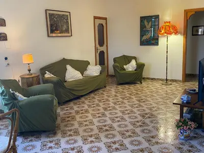 a living room with two green chairs and a lamp at Villa Melina in Carini
